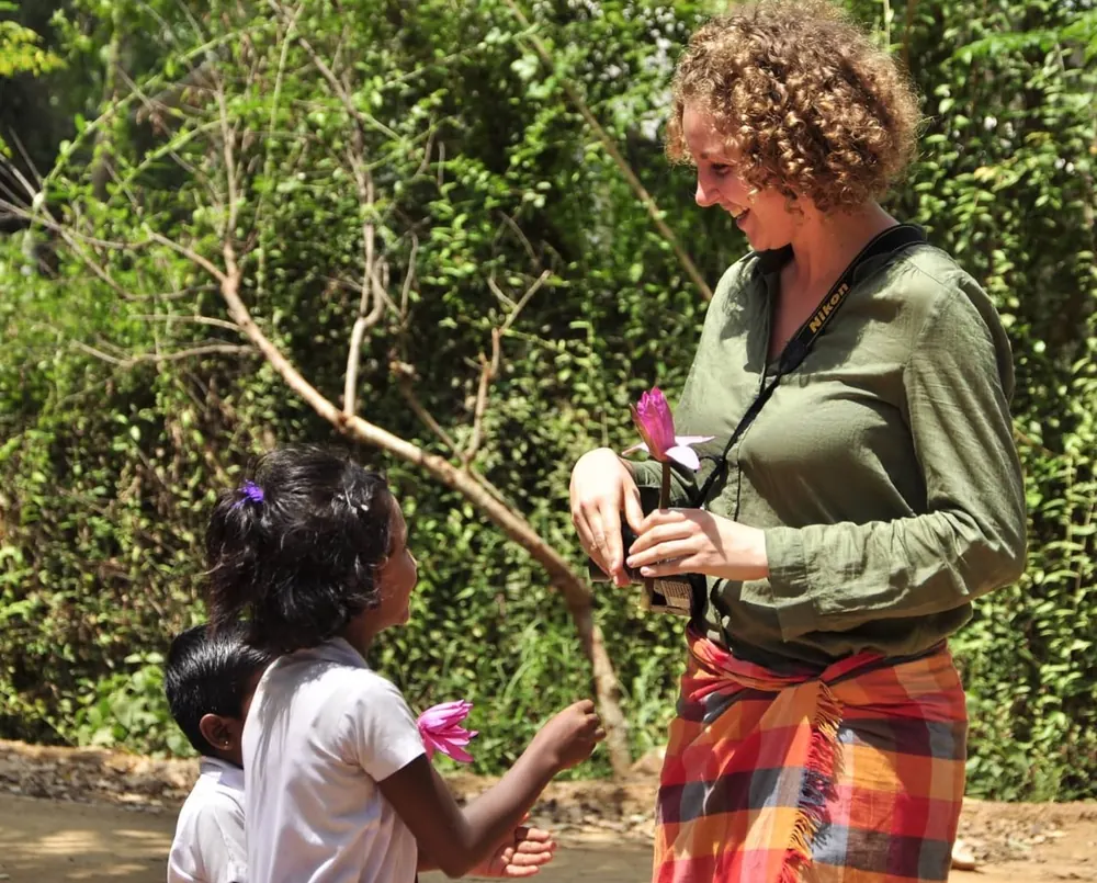 A guest sharing flowers with children during a community visit