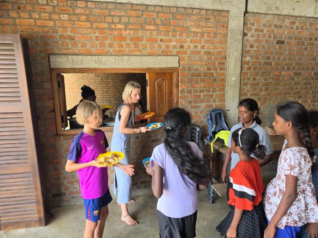 Guests serving fresh warm meals to local community children