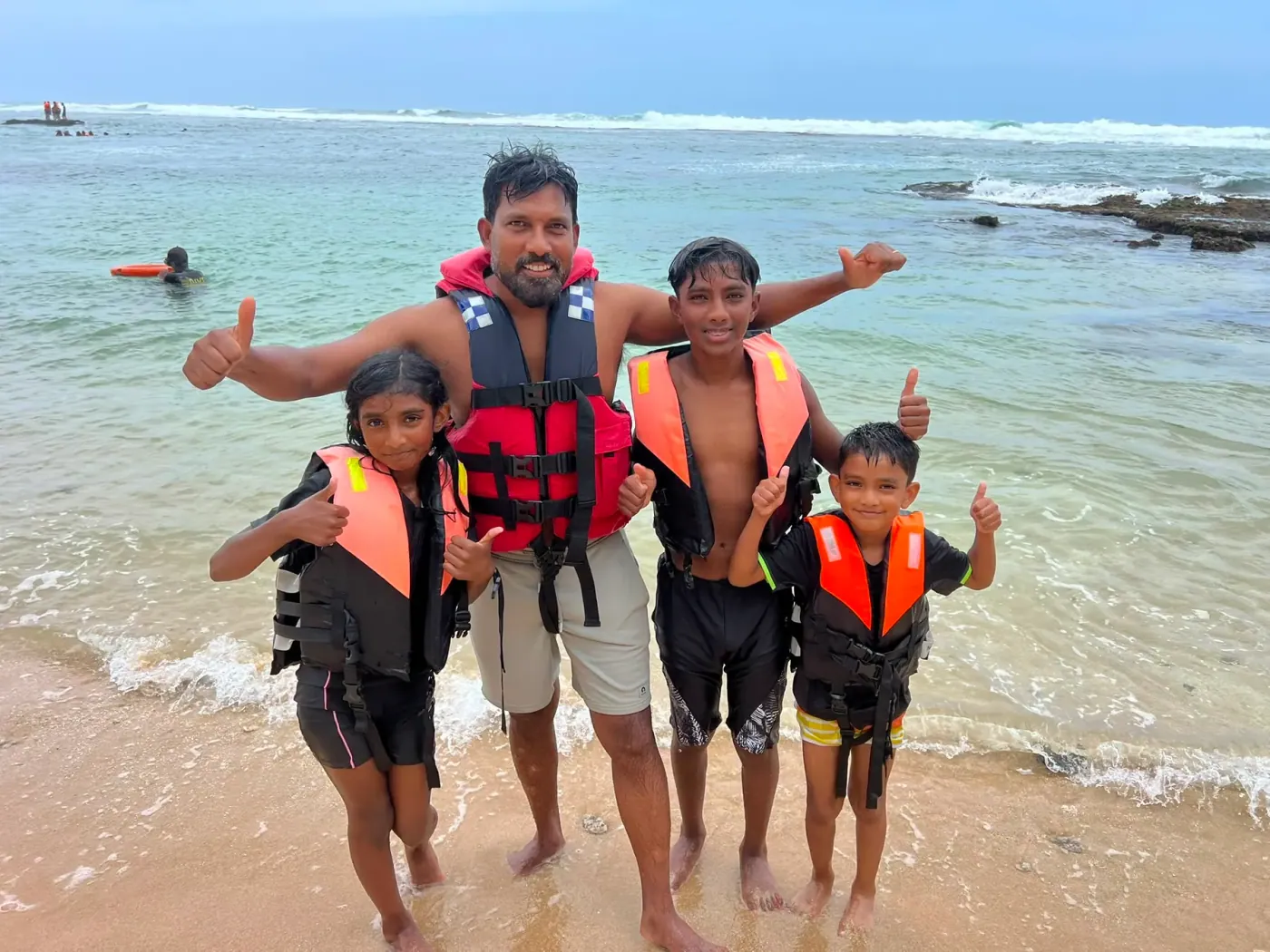 A family in life jackets on the beach before a water sports session