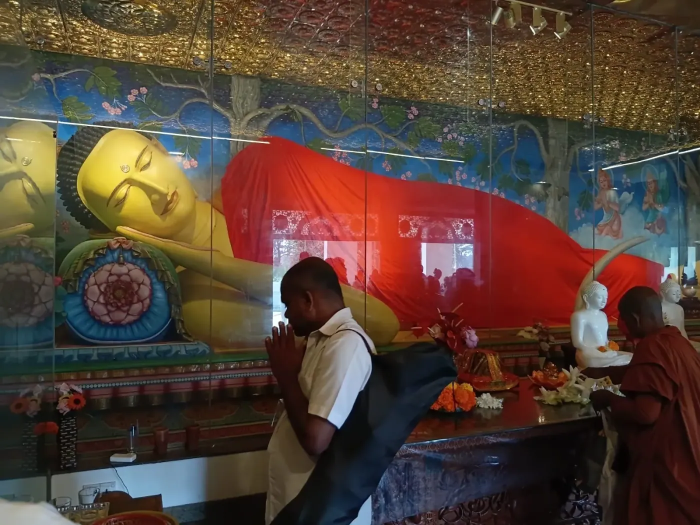 A guide offering flowers before a reclining Buddha