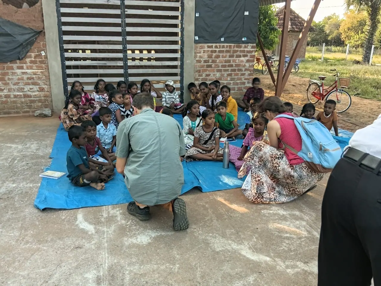 Guests sitting with village children during a community visit