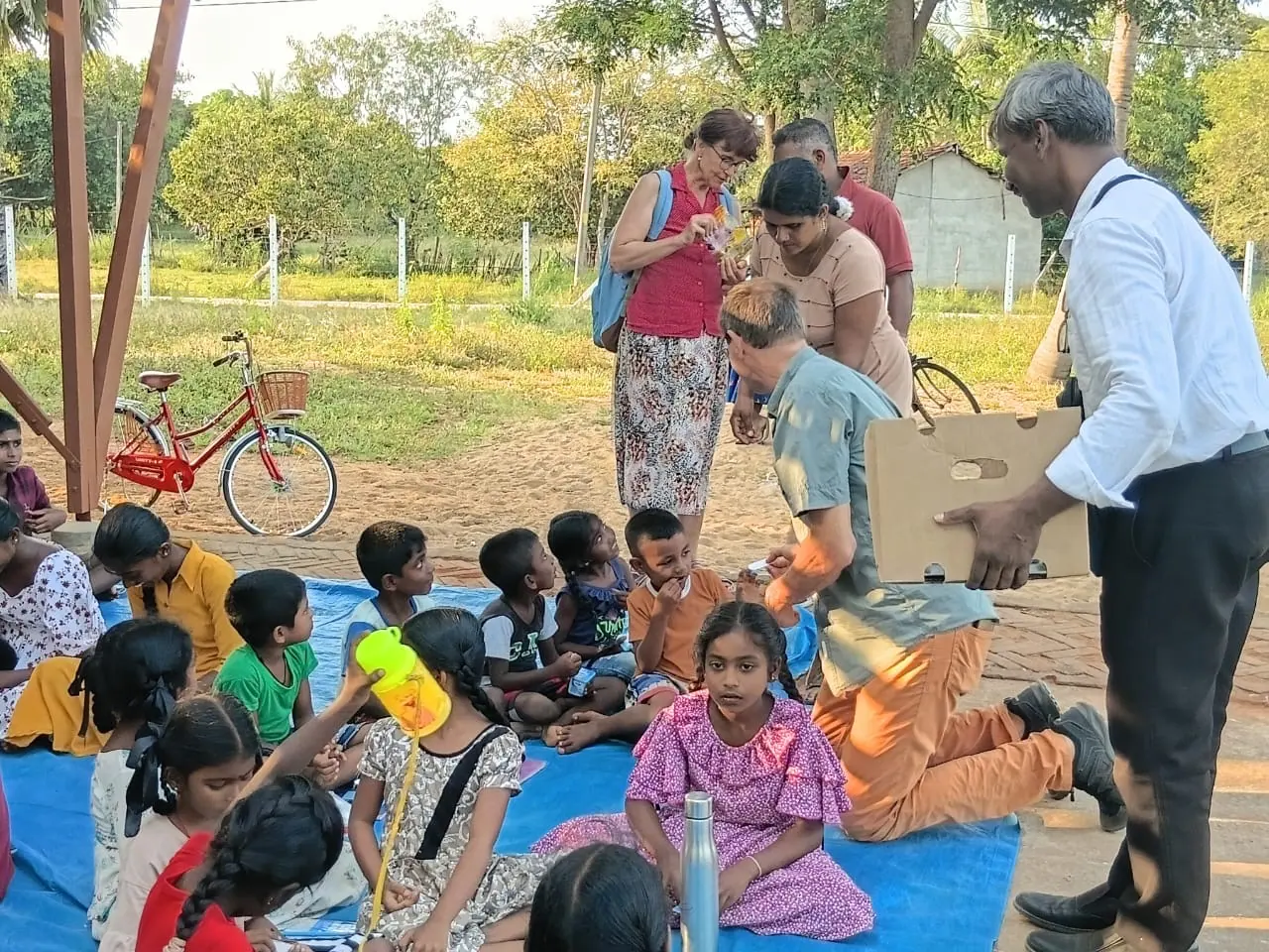 Guests handing out books to children at a village gathering