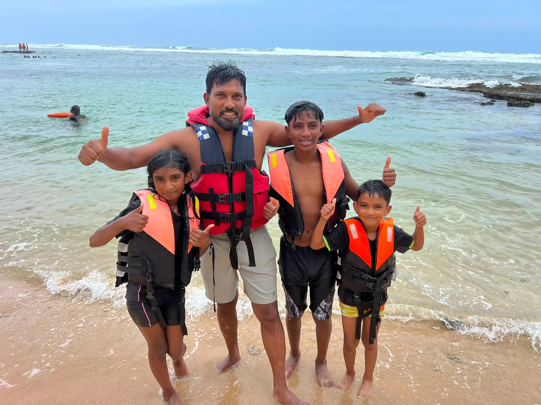 A family in life jackets on the beach before a water sports session